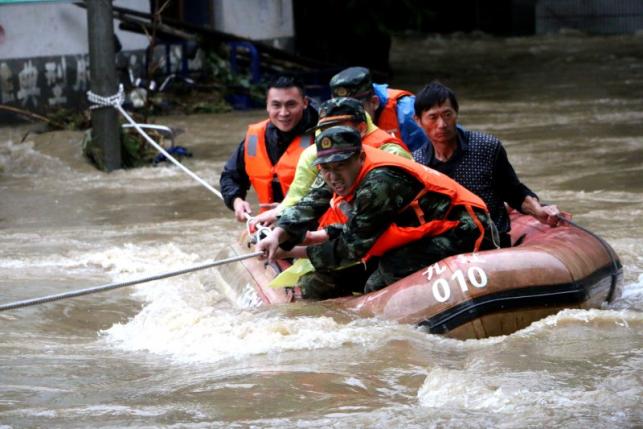 Rescuers grab a rope to prevent a raft carrying residents from being flushed away as residents are evacuated from a flooded area in Jiujiang, Jiangxi Province, China, June 19, 2016. REUTERS/Stringer