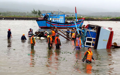 Vietnamese soldiers help rescue a sunken fishing boat on a river in the central province of Phu Yen on November 5, 2017, a day after Typhoon Damrey hit central Vietnam. / AFP PHOTO / Vietnam News Agency / STR